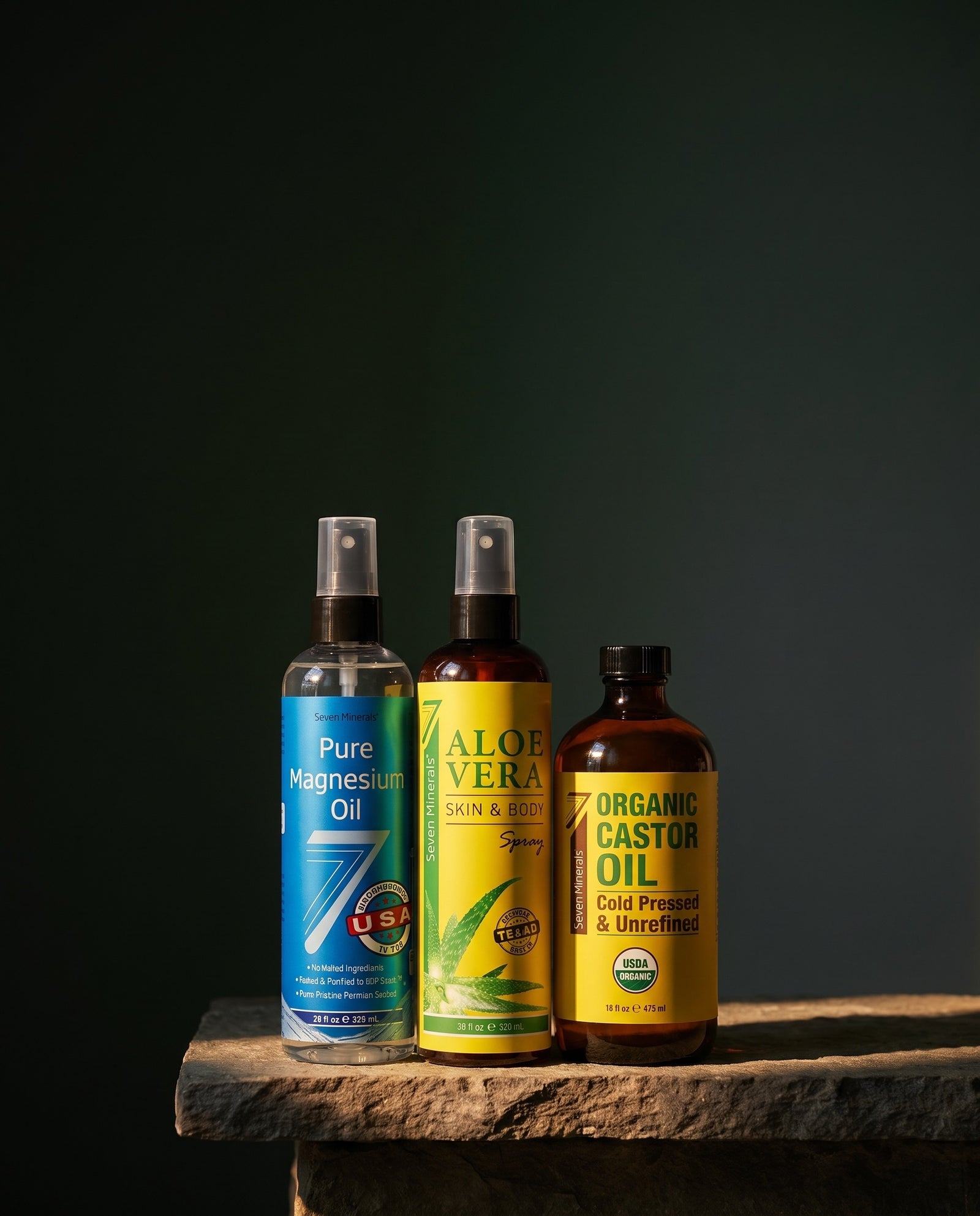 Seven Minerals magnesium oil, aloe vera spray and organic castor oil lit on a stone shelf