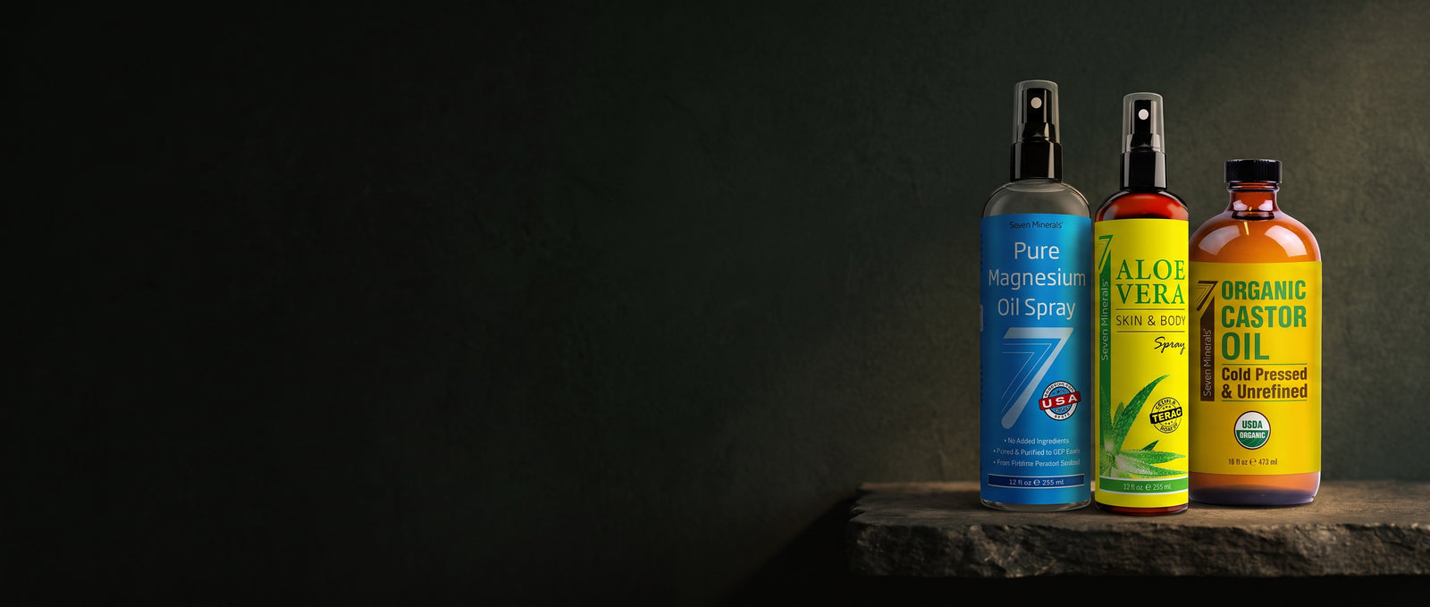 Seven Minerals magnesium oil spray, aloe vera spray and organic castor oil lit on a stone shelf